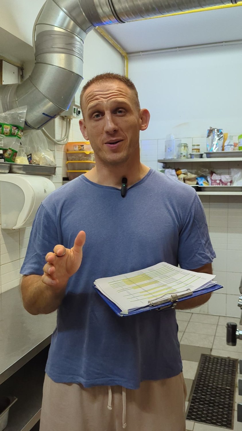 Paweł in a real kitchen, the day's production sheets in hand